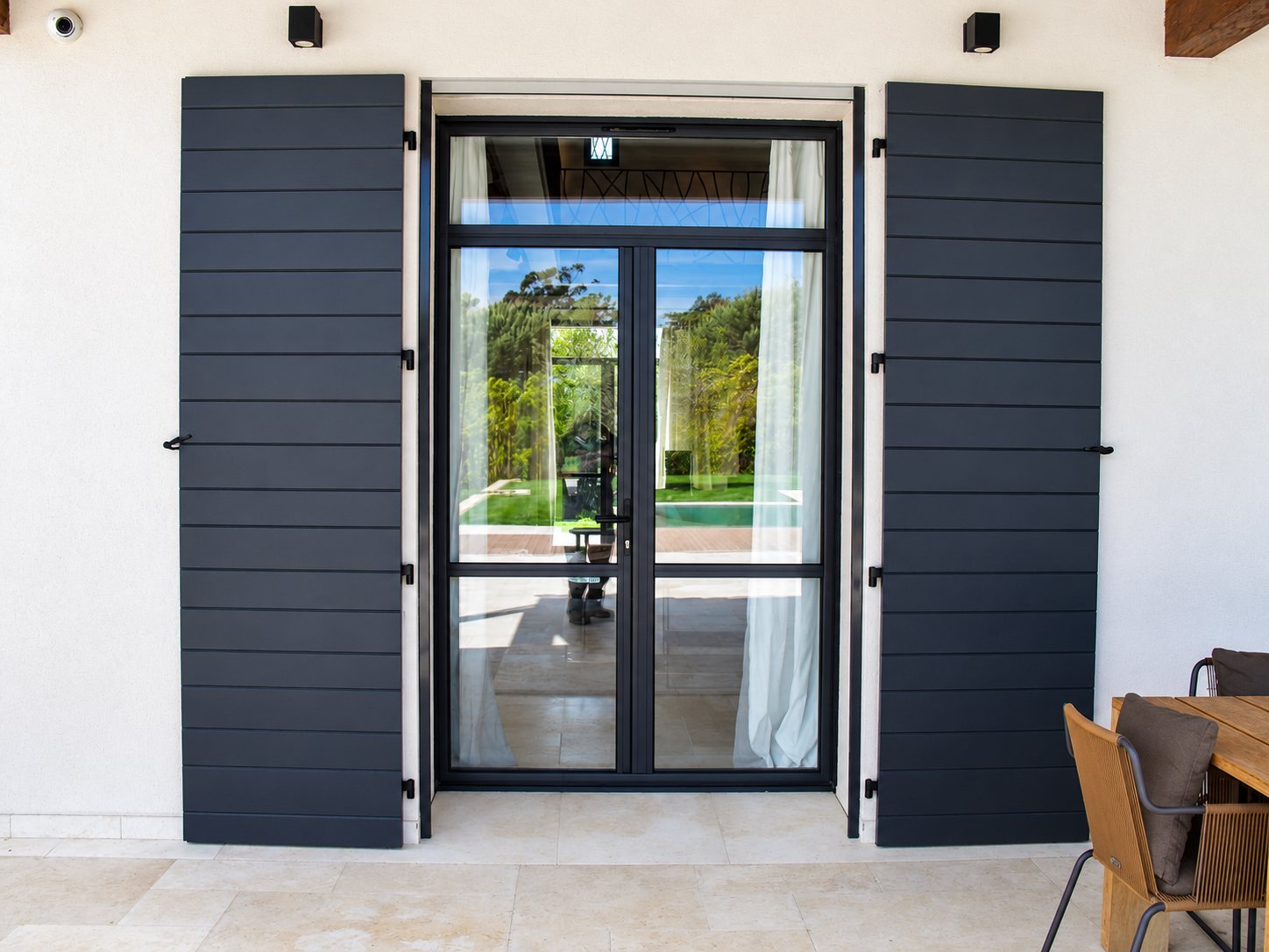 Façade blanche avec volets battants aluminium anthracite et porte-fenêtre posés par Olonne Fermetures